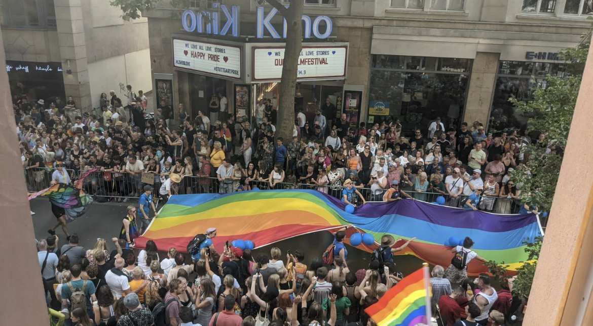 Parade-Teilnehmende tragen eine große Regenbogen-Fahne